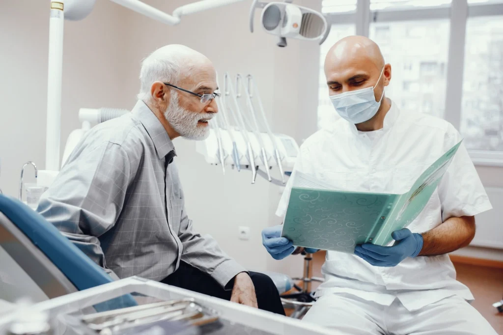 Older man consulting dentist about bone grafting before dental implants