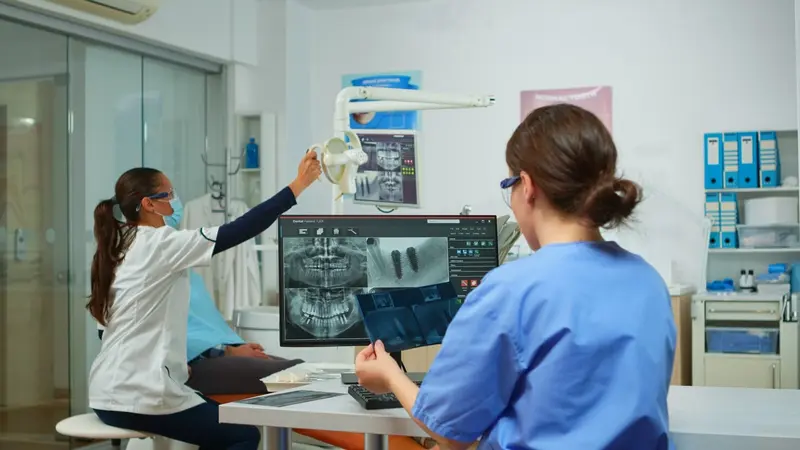 Dentist and assistant comparing dental radiographs for patient with toothache | Dental Implant Professionals Sydney